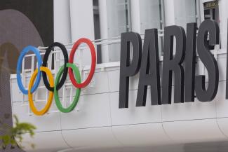 Die Olympischen Ringe und der Schriftzug "Paris" an der Fassade der Paris La Denfense Arena